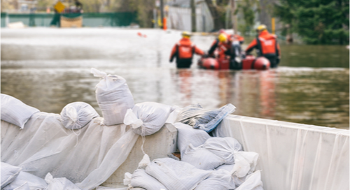 Workers walking a flotation device through a flooded street