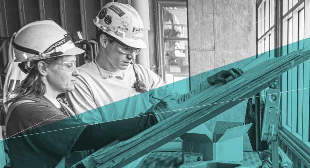 Two workers in safety gear reviewing plans