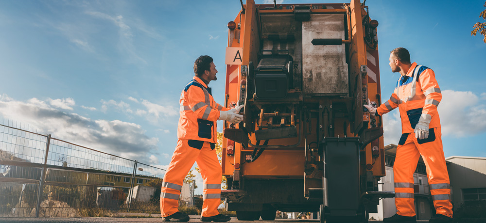 Waste and recycling workers loading waste onto a garbage truck.